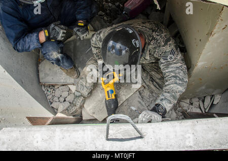 Two Airmen use hammer drills and heavy duty saws to make a hole in a concrete wall during a simulated search and rescue exercise at Volk Field, Wis. July 18, 2017. The PATRIOT North exercise is a Domestic Operations disaster-response training exercise conducted by National Guard units working with federal, state and local emergency management agencies and first responders. (U.S. Air National Guard photo by Master Sgt. Kellen Kroening/Released) Stock Photo