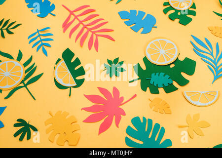 Tropical leaves and fruits pattern on a bright yellow background. Sunny summer colorful flat lay with paper cut outs. Stock Photo