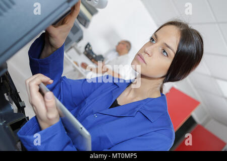 female technician servicing a printer using tablet computer Stock Photo