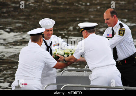 170718-N-WN521-017 MINNEAPOLIS (July 18, 2017) – Rear Adm. Frederick J. 'Fritz' Roegge, commander, Submarine Force, U.S. Pacific Fleet, and Hennepin County Sheriff Richard Stanek hand a floral wreath off to Chief Navy Diver Noah Gottesman and Navy Diver 1st Class Brian Bennett as part of a wreath-laying ceremony held under the I-35W bridge on the Mississippi River to remember those lost in the tragic bridge collapse ten years ago August 1. Both Gottesman and Bennett were attached to Mobile Diving and Salvage Unit (MDSU) 2 when they were called to assist local, state and federal authorities in  Stock Photo