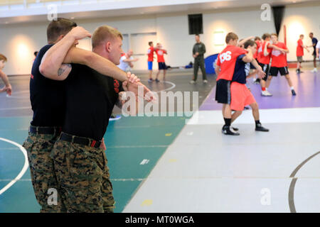 U.S. Marine Martial Arts Instructor Trainers with the Marine Corps Center of Excellence give a demonstration to young wrestlers during the United States Marine Corps Sports Leadership Academy at York College in York, Pa., July 18, 2017. The USMC Sports Leadership Academy combines athlete development with character building with Marines and coaches. (U.S. Marine Corps photo by Sgt. Devin Nichols/Released) Stock Photo