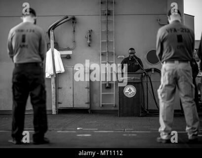 BAHRAIN (April 16, 2017) Lt. Solomon Lloyd, a Navy chaplain aboard the aircraft carrier USS George H.W. Bush (CVN 77) (GHWB), reads a prayer during a sunrise Easter service held on the flight deck. The George H.W. Bush Carrier Strike Group is deployed in the U.S. 5th Fleet area of operations in support of maritime security operations designed to reassure allies and partners, and preserve the freedom of navigation an the free flow of commerce in the region. Stock Photo