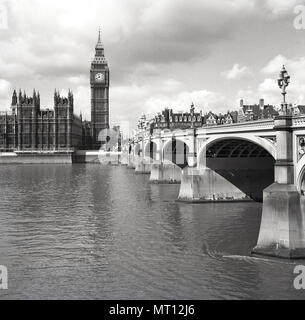 1950s, historical, view from the south across the River Thames showing Westminster Bridge and the Northern corner of the Palace of Westminster and the famous Clock tower - also known as 'Big Ben'. The palace is the meeting place of the two Houses of Parliament of the UK government and was designed by Charles Barry and Augustus Pugin. Stock Photo