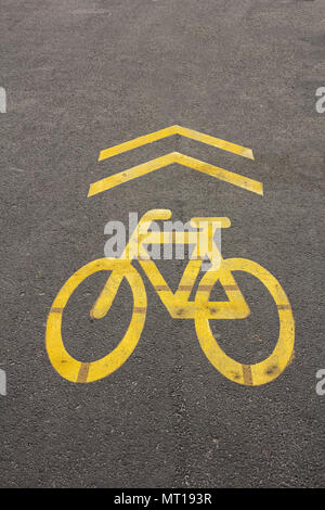 Yellow sign of a bicycle path drawn on the asphalt road. Lanes for cyclists. Cyclist on urban cycleway. Traffic signs and road safety. Stock Photo