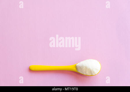 Spoon with sugar close-up on a pink background Stock Photo