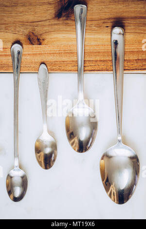 different spoons on stone marble wooden table background. Rustic vintage color toning. Stock Photo