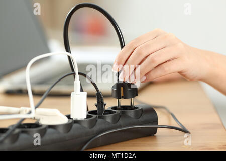 Close up of a woman hand plugging a plug in an electrical socket on a table at home Stock Photo