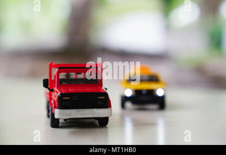 Red toy car truck and yellow old taxi car on road on blurred background,  traffic and drive concept Stock Photo