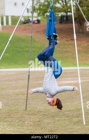 A young woman hangs upside down using fabric attached to poles, as she takes part in an aerial yoga class in Atlanta, GA, on April 8, 2018. Stock Photo