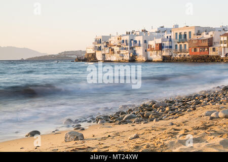 MYKONOS, GREECE - MAY 2018: View over the old Mykonos town district Little Venice with stony beach and sea on the foreground. Long exposure shot, wate Stock Photo