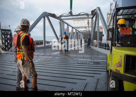 Workers aboard the USNS John Glenn help attach a ramp to the USNS Dahl during exercise Pacific Horizon 2017 July, 20, 2017.  This ramp serves as a connector between the two ships, allowing for movement of vehicles and supplies from one ship to the other. Pacific Horizon 2017 is a Maritime Prepositioning Force (MPF) exercise designed to train I Marine Expeditionary Force (MEF) and components of Naval Beach Group 1 (NBG-1) Marines and Sailors on arrival and assembly operations. (U.S. Marine Corps photo by Lance Cpl. Roxanna Gonzalez) Stock Photo