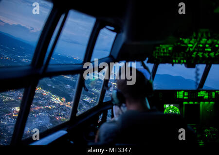 A C-130J Super Hercules pilot with the 36th Airlift Squadron, looks out the aircraft during a routine training mission July 18, 2017, over the Tokyo Metropolitan area, Japan. The routine training included low level flying, simulated heavy cargo drop and night operations including the loading and unloading of the aircraft. (U.S. Air Force photo by Airman 1st Class Donald Hudson) Stock Photo