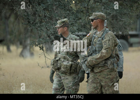 Capt. Elijah Murrell, right, of the Army Reserve’s 3rd Battalion, 383rd Regiment, 4th CAV MFTB in St. Louis, Mo., and lead observer coach/trainer for the 208th Transportation (Palletized Loading System) Company, briefs Maj. Gen. Todd McCaffrey, commanding general of First Army Division East, during a battlefield circulation review of Combat Support Training Exercise 91-17-03, July 18, 2017, at Fort Hunter Liggett, Calif. The 208th Transportation Company is an Army Early Response Force unit that must be ready to deploy with very short notice. Approximately 5,000 Army Reserve and National Guard  Stock Photo