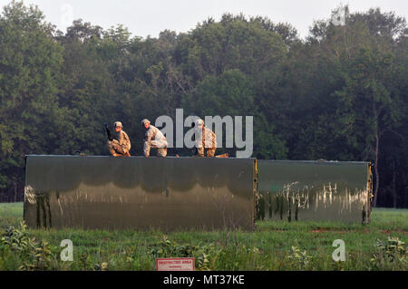 Three U.S. Army Soldiers from a Multi-Role Bridge Company kneel on top of an Improved Ribbon Bridge (IRB) Bay Section waiting to hook it up to a CH-47 Chinook of Company B, 7th (General Support Aviation) Battalion, 158th Aviation Regiment, 244th Aviation Brigade, Army Reserve Aviation Command during River Assault 2017 on Fort Chaffee Manuever Training Center, July 26, 2017. The Chinook dropped off the bay in the Arkansas River in order for the IRB to be built across the river, the culminating event of River Assault. Operation River Assault is one of the key training events that demonstrates th Stock Photo