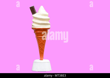 Vintage plastic promotional UK ice cream cone with vanilla whipped ice cream and a chocolate flake with a pink background Stock Photo