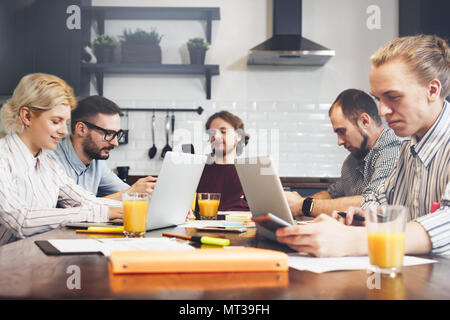 Teamwork on the kitchen and brainstorming on new startup project. Creative managers or students make great business. Work with laptops Stock Photo