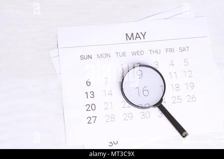 Concept image of business and meetings. Calendar to remind you an important appointment and Magnifying glass in May. Stock Photo
