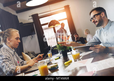 Two modern young businessman sit around table and work on laptop and tablet. Team of students are working on the coursework. Сoworking concept Stock Photo