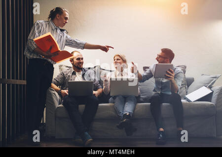 Team brainstorming with modern electronics device and gadgets on loft space. Group of coworkers working on a new startup Stock Photo
