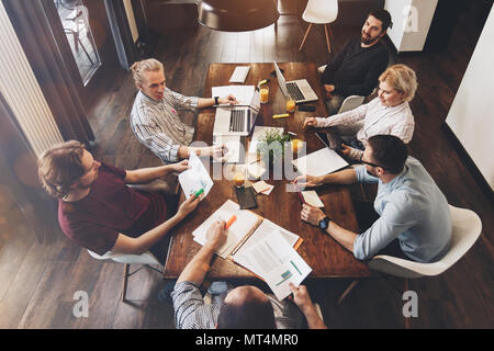 Top view shot of business people in modern office. Men and women working on electronics devices in office space. Group of young people working togethe Stock Photo