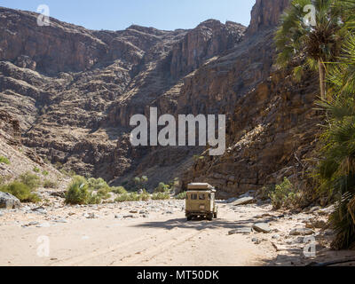 Purros, Namibia - July 26, 2015: 4x4 offroad vehicle driving in dry river bed of Hoarusib River with mountains Stock Photo