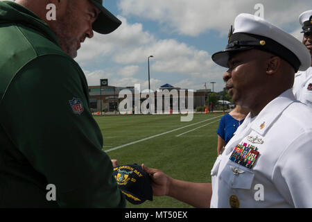 170728-N-CU914-218 GREEN BAY, Wis. (July 28, 2017) – David Robinson Jr., Command Master Chief, USS Green Bay (LPD 20), presents Green Bay Packers head coach, Mike McCarthy, with a USS Green Bay ship’s ball cap on the sidelines of the Packers’ practice field, during Green Bay/Fox Cities Navy Week. Navy Week programs serve as the U.S. Navy's principal outreach effort into areas of the country that lack a significant Navy presence, helping Americans understand that their Navy is deployed around the world, around the clock, ready to defend America at all times. (U.S. Navy photo by Mass Communicati Stock Photo