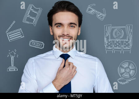 Cheerful actor touching his tie and feeling confident Stock Photo