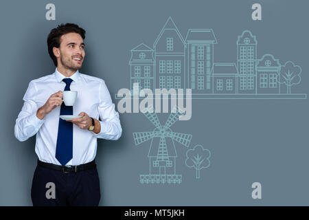Calm man looking at the beautiful houses while drinking coffee Stock Photo