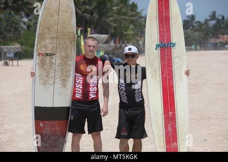 Mirissa/Sri Lanka - April 4, 2018: Two sports men stand on the beach with surfboards. Stock Photo