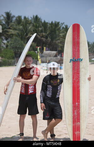 Mirissa/Sri Lanka - April 4, 2018: Two sports men stand on the beach with surfboards. Stock Photo