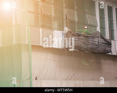 workers in suspended platform working to cutting steel out of new building. Stock Photo