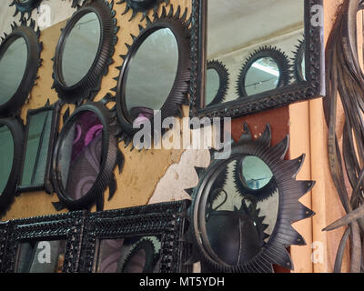 Mirrors in black metal curly frames on the wall of the house, for sale. Stock Photo