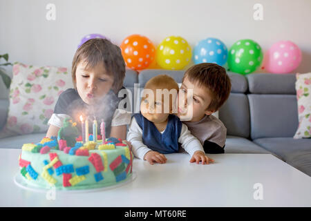 Cute children, boy brothers, celebrating  birthday with colorful cake, candles, balloons at home Stock Photo