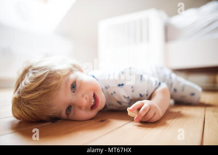 A toddler boy on the floor in the bedroom at home. Stock Photo