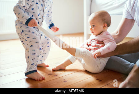 Father and toddler children sitting on the floor at home at bedtime. Stock Photo