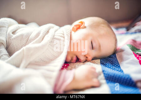 A toddler girl sleeping on a bed at home. Stock Photo