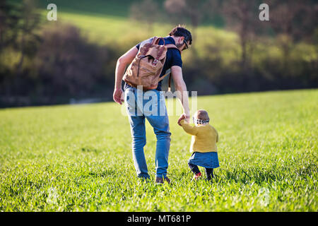 A father with his toddler daughter on a walk outside in spring nature. Stock Photo