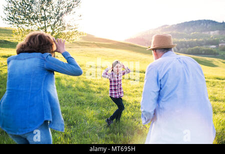 A small girl with her senior grandparents having fun outside in nature. Stock Photo