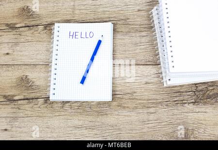 Marker pen and notebooks on wooden board written: HELLO Stock Photo