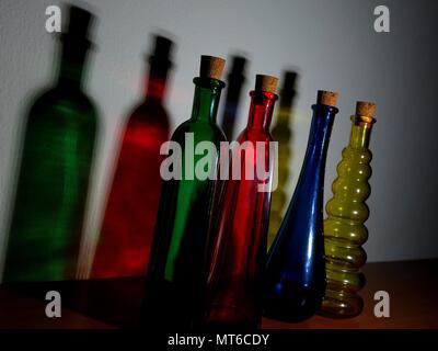 Colored bottles casting shadows on wall. Stock Photo