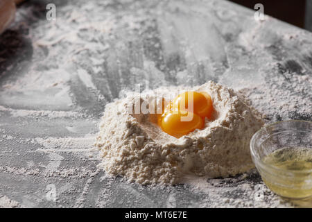 Two yolks and flour on the kitchen table. Ingredients for dough. Stock Photo