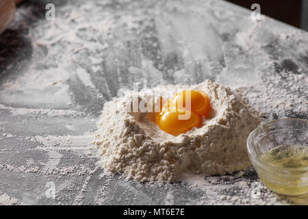 Two yolks and flour on the kitchen table. Ingredients for dough. Stock Photo