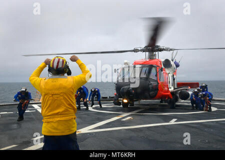 Coast Guard Petty Officer 1st Class Sean Carrillo signals to crew members during helicopter operations onboard the Coast Guard Cutter Healy while on patrol off the coast of Alaska, July 28, 2017. The Coast Guard has a long history of Arctic operations and possesses unique capabilities to ensure the region is stable, secure, and developed in a sustainable manner. Coast Guard photo by Petty Officer 2nd Class Meredith Manning Stock Photo