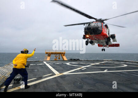 Coast Guard Petty Officer 1st Class Sean Carrillo signals to an Air Station Kodiak MH-60 Jayhawk helicopter crew during helicopter operations on board the Coast Guard Cutter Healy, July 28, 2017. The Coast Guard has a long history of Arctic operations and possesses unique capabilities to ensure the region is stable, secure, and developed in a sustainable manner. Coast Guard photo by Petty Officer 2nd Class Meredith Manning Stock Photo