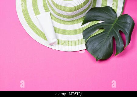 on green monstera leaf with sunglasses and straw hat on pink marble table Stock Photo