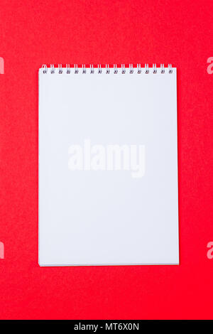 Top view of open spiral blank notebook on red paper background Stock Photo