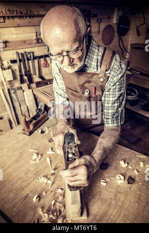 senior carpenter use handplaner in his workshop Stock Photo
