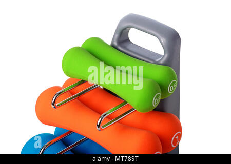 Set of colored isolated dumbbells for sport on a white background folded on a special gray stand. Stock Photo