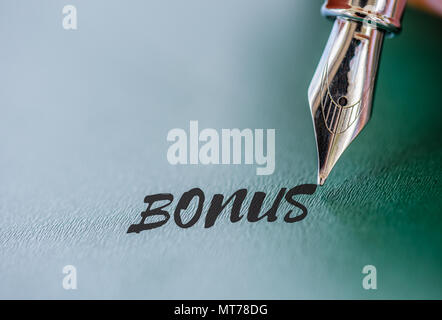 Abstract pen writing Bonus word on green board. Business achievement concept. Stock Photo