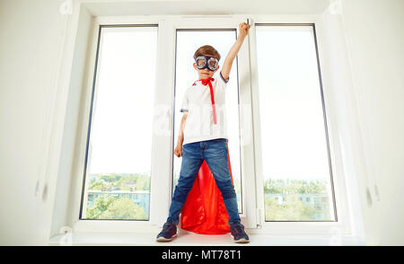The boy in the costume of a superhero at the window Stock Photo